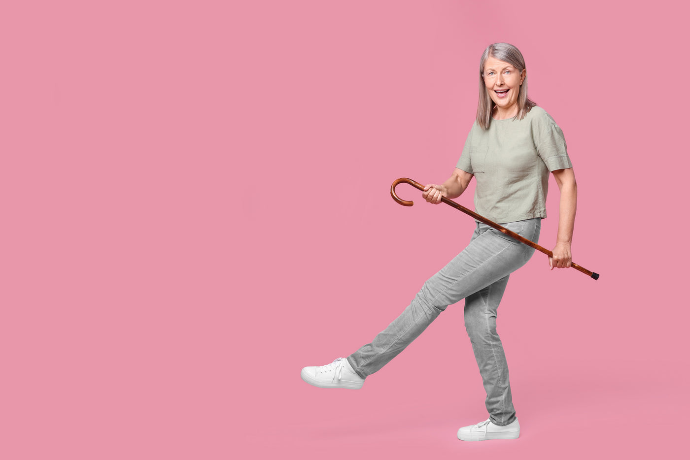 Glad dame der danser med spadserstok i hænderne